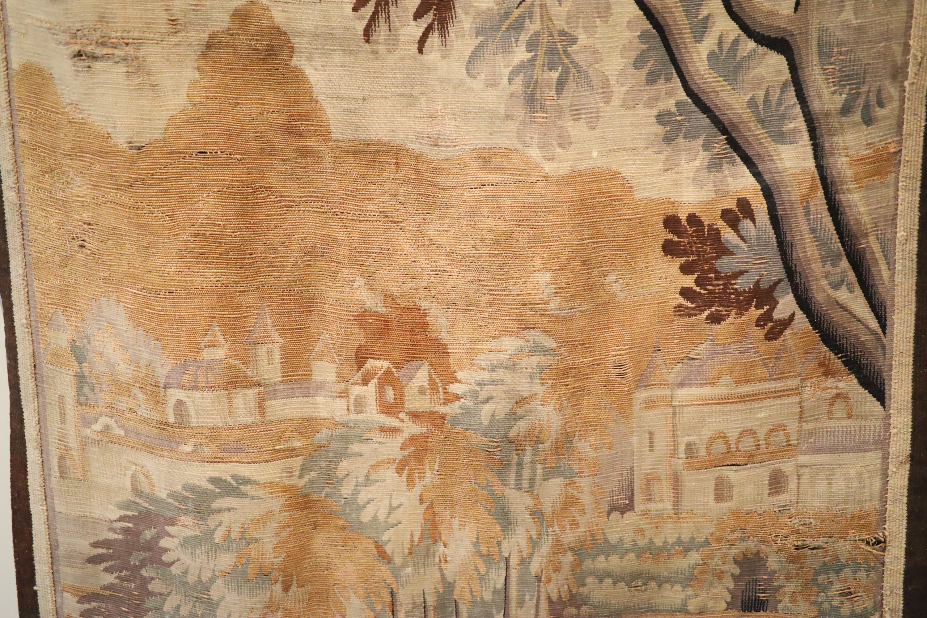 A French tapestry wall hanging, decorated with a town and trees, 125 x 79cm, with associated wrought iron hanging rail